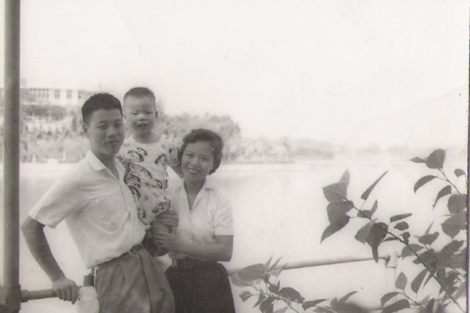 The young Chang family with their first son Nathan beside a body of water, ~1960