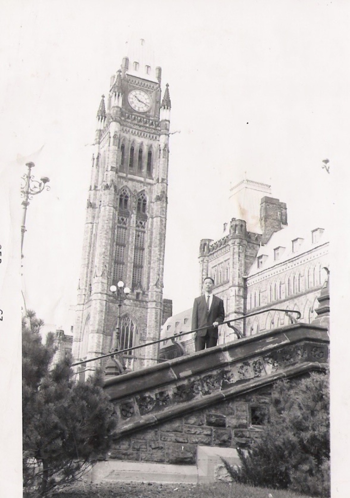 Shinn-Der Chang standing in front of the Parliament Building clock tower, Ottawa, 1963