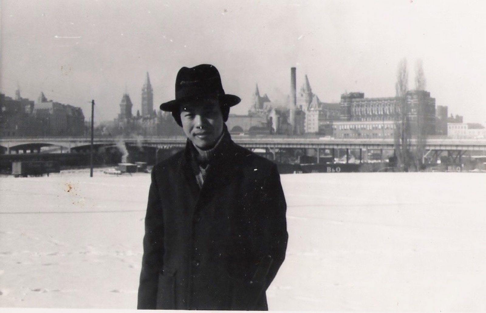 Shinn-Der Chang in a coat and hat standing in the snow, Ottawa, December 1964