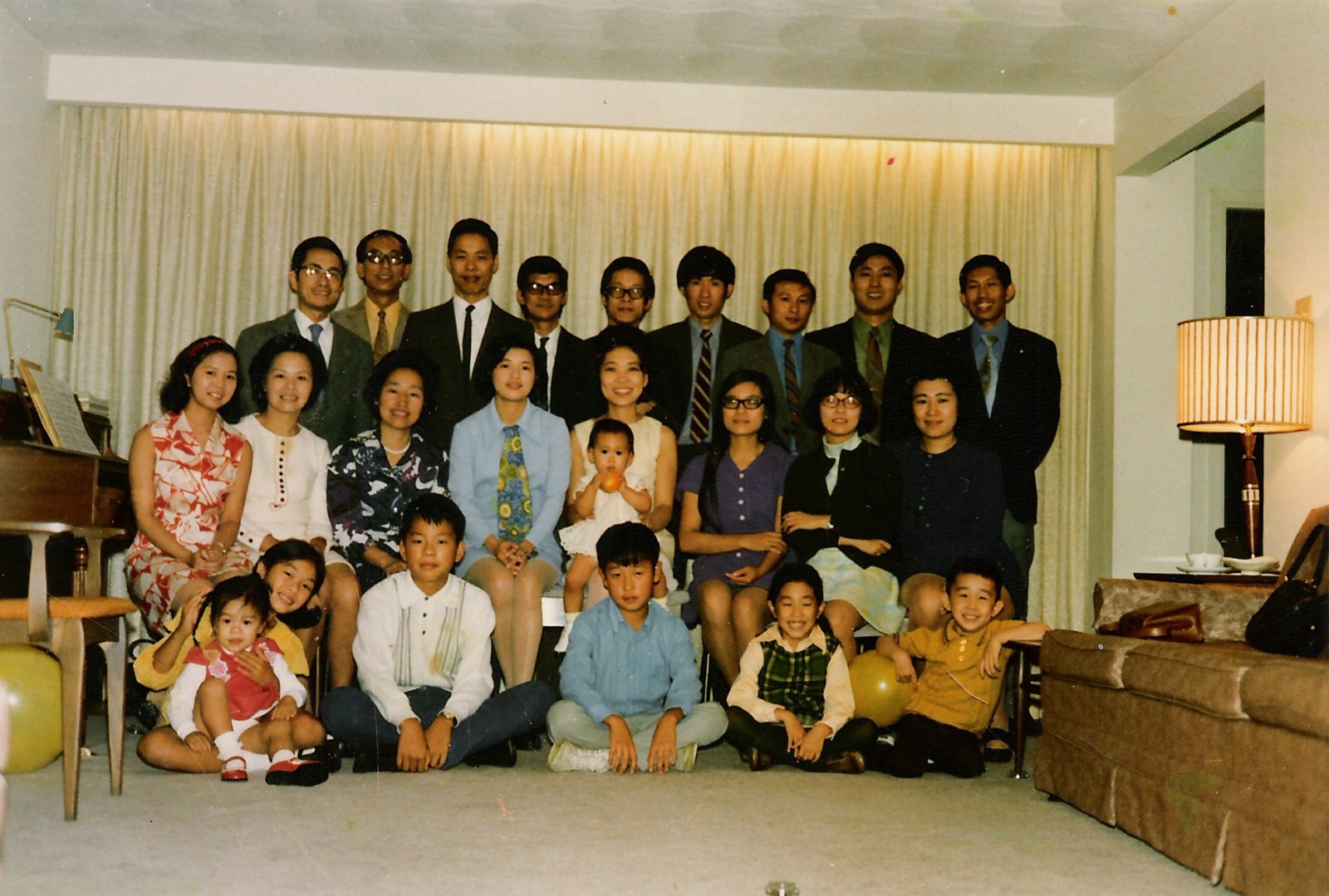 A large group of friends and children gathered for a portrait in a living room, 1970