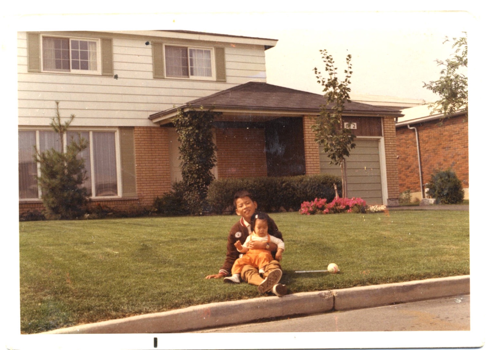 A child sitting on the front lawn of 612 Tubman Crescent, Ottawa, 1970