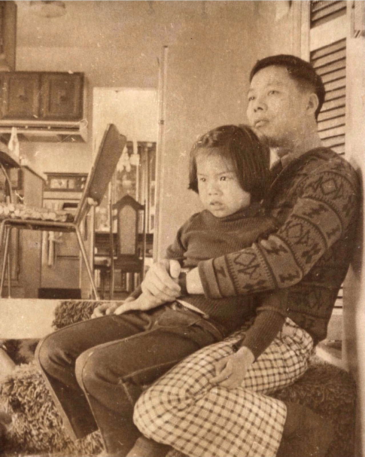 Shinn-Der Chang seated on a couch with a young Margaret, 1974