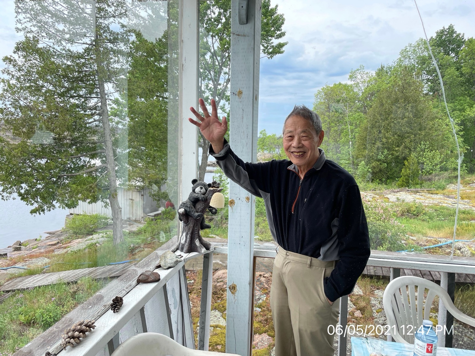 Shinn-Der Chang outside the cottage with a hand raised, June 2021